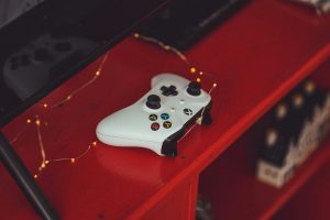 White game controller on red shelf with fairy lights, indie game development vibe